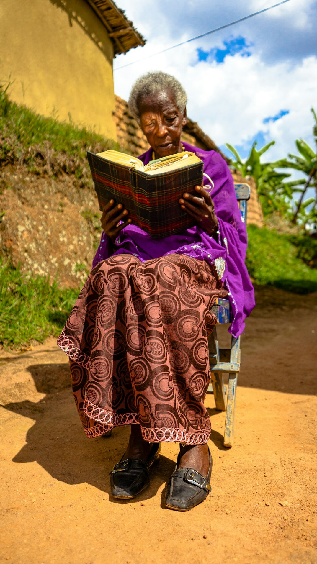 Senior woman with short grey hair and glasses reading in an armchair