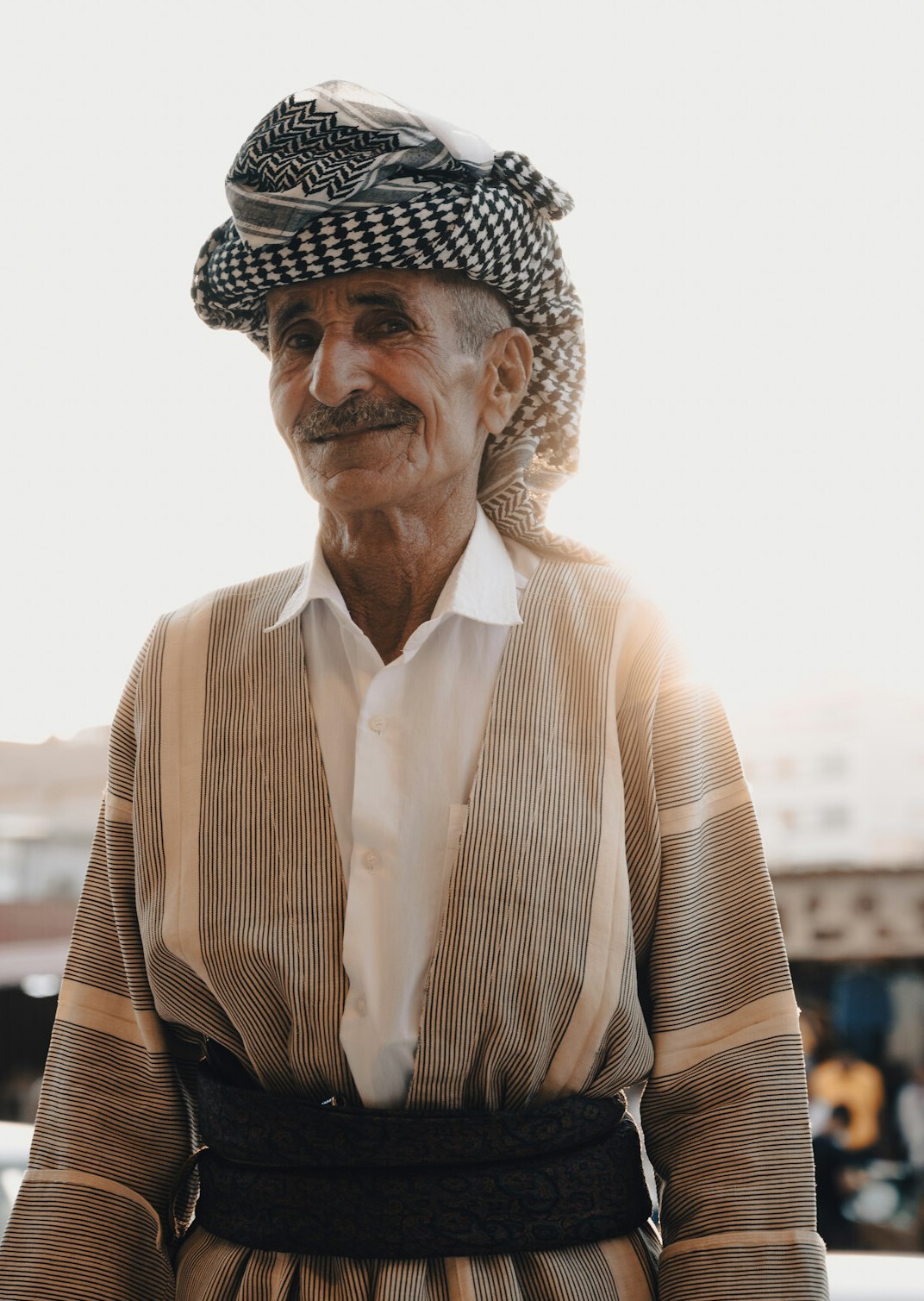 Senior woman with wavy white hair and a light scarf smiling