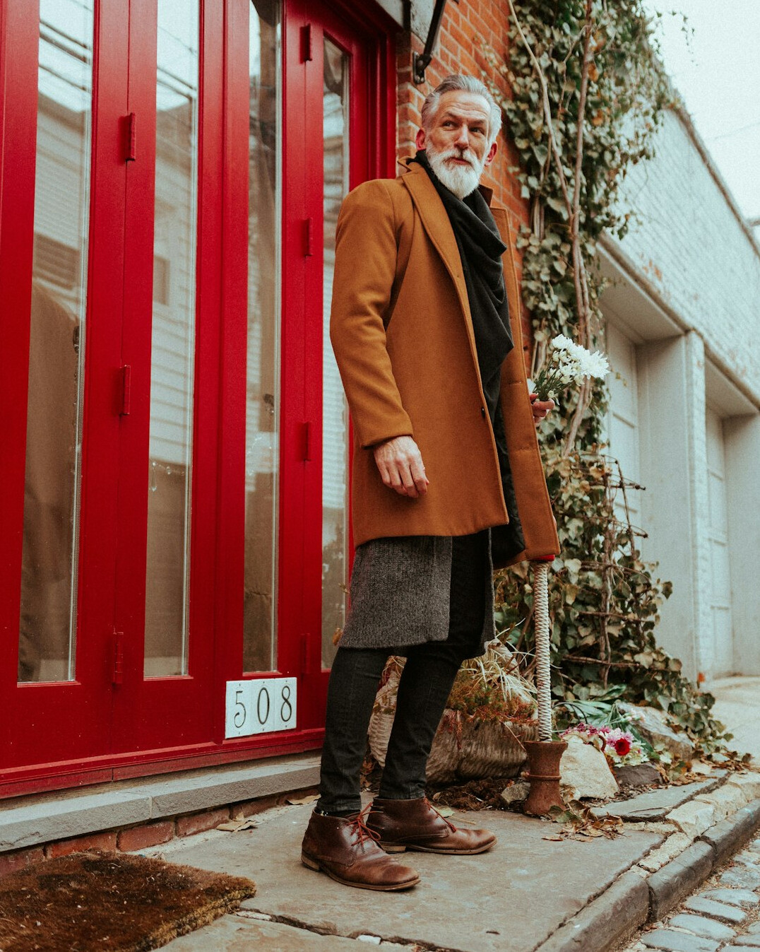 Senior man with grey beard smiling outdoors in a woolen jacket